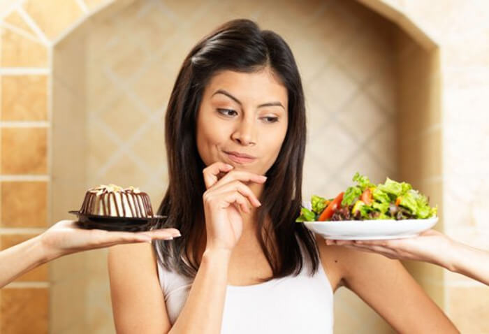 Žena bira između zdravog i nezdravog obroka.