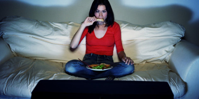 Žena jede dok gleda televiziju